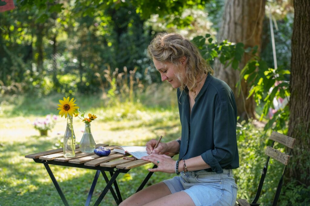 Lucia Steinbacher schreibend in ihrem Garten mit ihren Blumen